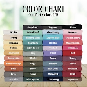 Puede incluir: Una carta de colores para camisetas Comfort Colors 1717, que muestra una gran pila de muestras de tela dobladas en varios tonos. Cada muestra est&aacute; etiquetada con su nombre de color espec&iacute;fico, incluyendo tonos blancos, negros, azules, verdes, rojos y marrones.