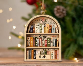 May include: Wooden bookshelf ornament with a floral design and the name "Rick" on the bottom shelf. The ornament features miniature books with colorful floral and leaf patterns, and a gold string for hanging.