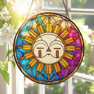 Può includere: Un acchiappasole rotondo in vetro colorato con un design a forma di sole stilizzato. Il sole ha un volto bianco con dettagli marroni ed è circondato da raggi dorati. Lo sfondo presenta un mosaico di vetro blu, verde, viola e giallo.