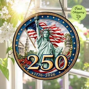 Könnte beinhalten: Ein rundes Hängeschild mit der Freiheitsstatue, die eine Fackel und eine Tafel hält, vor einer großen amerikanischen Flagge. Die Zahl 250 ist in Gold hervorgehoben, darunter stehen die Jahreszahlen 1776-2026 in einem blauen Rand.