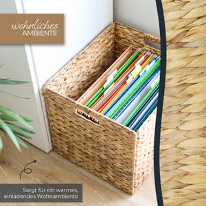 Può includere: Un cesto rettangolare in giacinto d'acqua intrecciato con manici integrati, riempito con cartelle sospese colorate. Il cesto presenta una texture intrecciata color marrone chiaro naturale e contiene varie cartelle verdi, rosse e blu.
