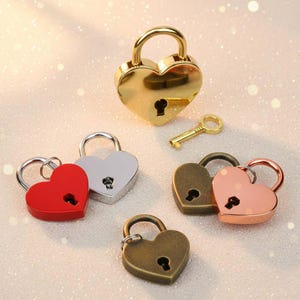 Può includere: Una collezione di lucchetti a forma di cuore in varie finiture metalliche: oro, argento, rosso, bronzo e oro rosa. È presente anche una piccola chiave d'oro. Questi lucchetti decorativi sono ideali per la creazione di gioielli o progetti artigianali.