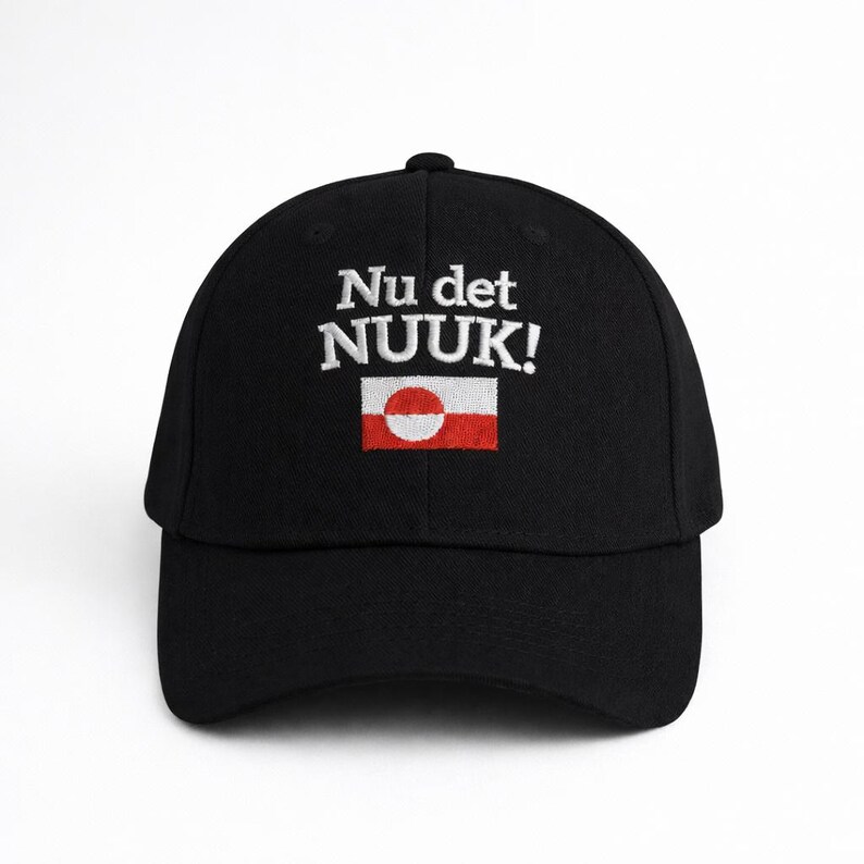 Puede incluir: Gorra de b&eacute;isbol negra con la inscripci&oacute;n blanca bordada "Nu det NUUK!". Debajo, una peque&ntilde;a bandera groenlandesa bordada, con un c&iacute;rculo blanco sobre fondo rojo.