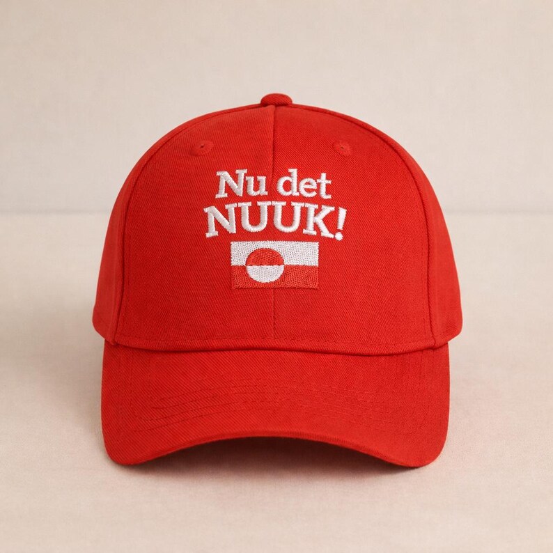 Puede incluir: Gorra de b&eacute;isbol roja brillante con el texto bordado "Nu det NUUK!" en blanco. Debajo del texto hay un peque&ntilde;o parche rectangular con un dise&ntilde;o blanco y rojo. La gorra tiene una visera curva y una corona redondeada.