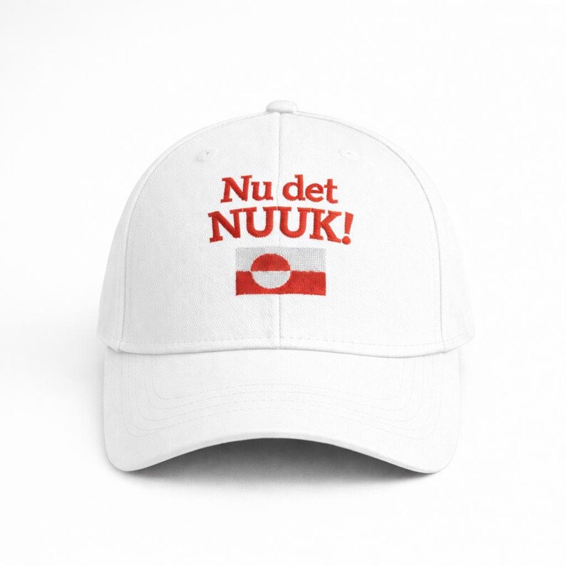 Puede incluir: Gorra de b&eacute;isbol blanca con el texto rojo "Nu det NUUK!" y un dise&ntilde;o de bandera roja y blanca. La gorra tiene una visera curva y una corona estructurada, adecuada para uso casual.
