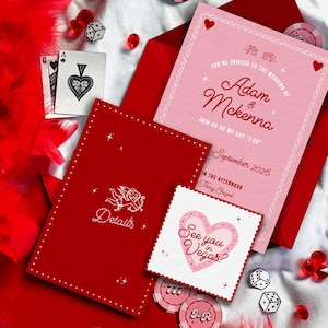 Könnte beinhalten: Eine Hochzeitseinladungssuite mit Las Vegas-Thema. Die Suite enthält eine rosa Einladung mit den Namen "Adam & McKenna" und dem Datum "September 2026". Rote Umschläge, Spielkarten, Würfel und Pokerchips vervollständigen das Design.