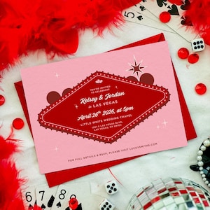 May include: A pink wedding invitation with a red border and a Las Vegas theme. The invitation includes the names Kelsey & Jordan, the date April 26th, 2026, and the location. The image also includes playing cards, dice, and a disco ball.