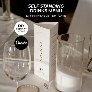 May include: A white, self-standing drinks menu with the word "DRINKS" in elegant script. The menu is a DIY printable template. The image also includes a wine glass and a tall, clear glass. Text on the menu reads "DIY PRINT AT HOME" and "Canva".