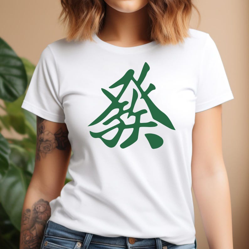 K&ouml;nnte beinhalten: Wei&szlig;es T-Shirt mit einem gro&szlig;en, stilisierten gr&uuml;nen Grafikdesign. Das Design ist ein abstraktes Symbol oder Zeichen. Das T-Shirt hat kurze &Auml;rmel und ist aus weichem Material.