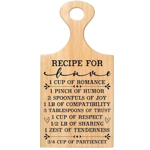 May include: Wooden cutting board with a handle, featuring the text "RECIPE FOR love" in black script. The recipe includes ingredients like romance, humor, joy, and trust, with measurements in cups, pinches, and tablespoons.