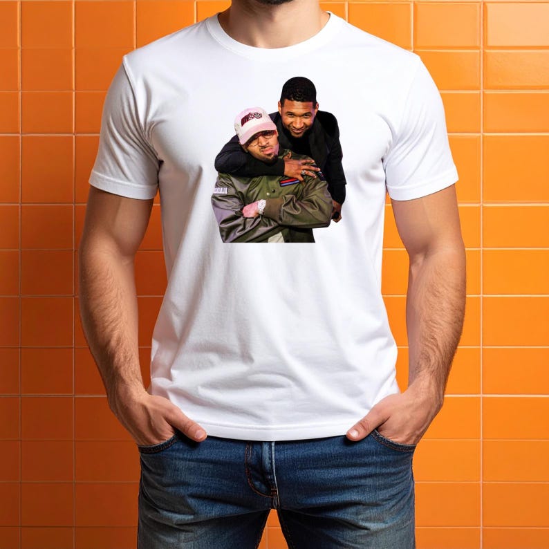 Pu&ograve; includere: Una t-shirt bianca a maniche corte con una stampa grafica di due persone. Una persona indossa un berretto da baseball rosa e una giacca verde oliva scuro, mentre l'altra persona sta dietro indossando un blazer nero sopra una camicia nera.