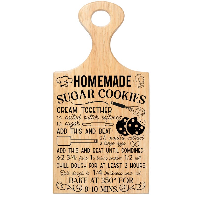 May include: Wooden cutting board with a handle, featuring a recipe for homemade sugar cookies. The text includes ingredients and baking instructions, such as "Bake at 350&deg; for 9-10 mins." The board has a light wood grain.