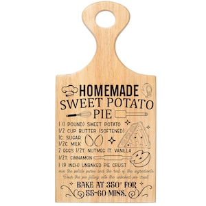 May include: Wooden cutting board with a handle, featuring a recipe for homemade sweet potato pie. The recipe includes ingredients like sweet potato, butter, sugar, milk, eggs, nutmeg, vanilla, cinnamon, and an unbaked pie crust. The board is designed to be baked at 350 degrees Fahrenheit for 55-60 minutes.