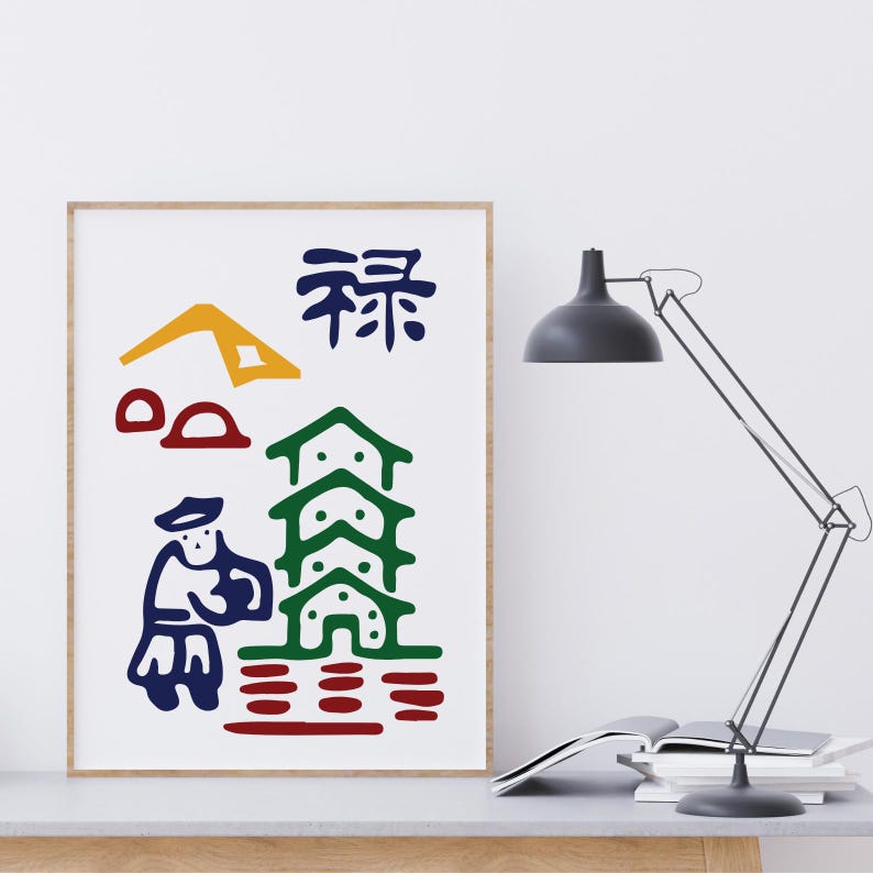 K&ouml;nnte beinhalten: Abstrakter Kunstdruck in einem Holzrahmen. Das Kunstwerk zeigt ein farbenfrohes Design mit einem gelben Berg, roten Formen, einem gr&uuml;nen Geb&auml;ude, einer blauen Figur und blauen japanischen Schriftzeichen auf wei&szlig;em Hintergrund. Eine moderne Schreibtischlampe und B&uuml;cher sind im Hintergrund.