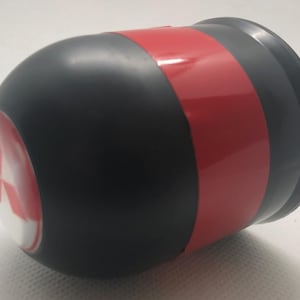 May include: A black and red cylindrical object with a white and red logo on one end. The object has a red band around the middle and a black base. The logo appears to be a stylized emblem.