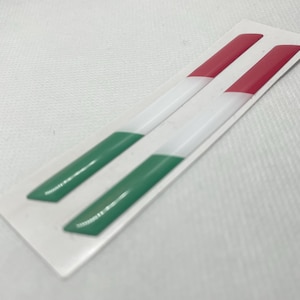 May include: Two green, white and red striped vinyl decals. The decals are shaped like long, thin rectangles.