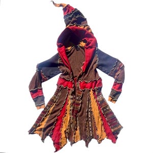 May include: A long-sleeved hooded jacket featuring a patchwork design in shades of brown, red, and orange. The garment has a pointed hood, exposed raw-edge seams, and a flared hemline with alternating solid-colored and patterned fabric panels.