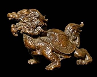 May include: A bronze-colored sculpture of a mythical creature with a dragon's head and a turtle's shell. The creature has detailed scales, a flowing mane, and a curled tail. The sculpture is set against a black background.