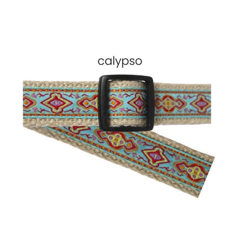 Pode incluir: Um cinto bege com fivela preta e um design estampado em turquesa, vermelho e amarelo. A palavra "calypso" est&aacute; impressa acima do cinto.