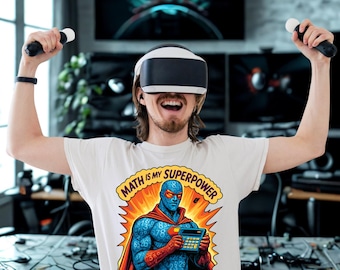 Può includere: Una maglietta bianca con la scritta "MATH IS MY SUPERPOWER" e una grafica di supereroe. Il supereroe è blu con un mantello rosso e tiene in mano una calcolatrice. La persona nell'immagine indossa un visore VR e tiene in mano dei controller.