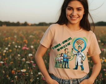 Könnte beinhalten: Hellpfirsichfarbenes T-Shirt mit einer Cartoon-Grafik eines IT-Ingenieurs, der ein Stethoskop an einem WLAN-Symbol verwendet. Der Text lautet: "IT ENGINEER - SAVING LIVES, ONE WIFI AT A TIME."