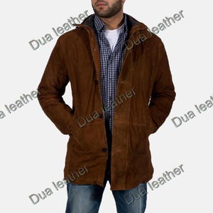 Peut inclure: Veste à capuche en daim marron avec fermeture boutonnée et poches. La veste est portée sur une chemise à carreaux et un sous-vêtement blanc. La veste porte l'inscription "Dua leather".