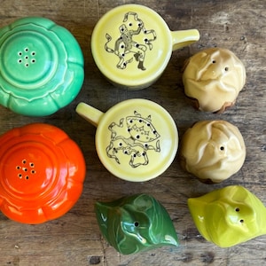 May include: A set of eight vintage ceramic salt and pepper shakers. The shakers are in various colors, including green, orange, yellow, and brown. Some of the shakers have a floral design, while others have a geometric design.