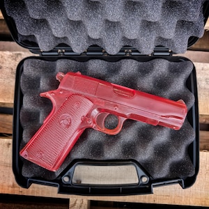 May include: A red plastic replica of a handgun in a black hard case with foam lining.