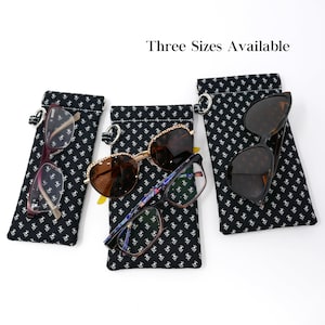 May include: Three eyeglass cases with glasses inside. The cases are black with a white floral pattern. The glasses include a pair of red-framed glasses, a pair of gold-rimmed sunglasses, and a pair of black sunglasses. The text "Three Sizes Available" is at the top.