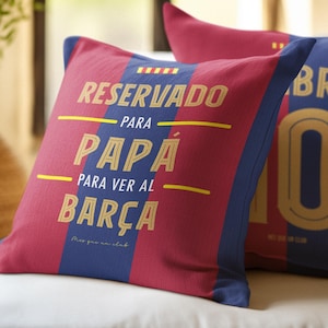 May include: Two decorative throw pillows with a red and blue striped design. One pillow has the text "RESERVADO PARA PAPÁ PARA VER AL BARÇA" in gold lettering. The other pillow has the number "10" in gold.