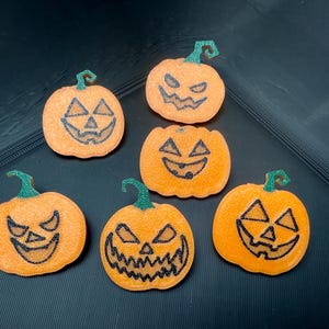 Può includere: Sei decorazioni a forma di zucca arancione con facce nere sorridenti di jack-o'-lantern e steli verdi glitterati. Queste decorazioni a tema Halloween sono perfette per aggiungere un tocco festoso.
