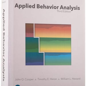 May include: A white textbook titled "Applied Behavior Analysis, Third Edition." The cover features a colorful geometric design with shades of orange, yellow, green, and blue. The authors' names are listed below the title. The book's spine also displays the title and author's names.