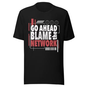 Può includere: T-shirt nera con la scritta "GO AHEAD BLAME the NETWORK" in bianco e rosso. Il design include forme geometriche e tre grafiche a globo. Un codice a barre è in basso.