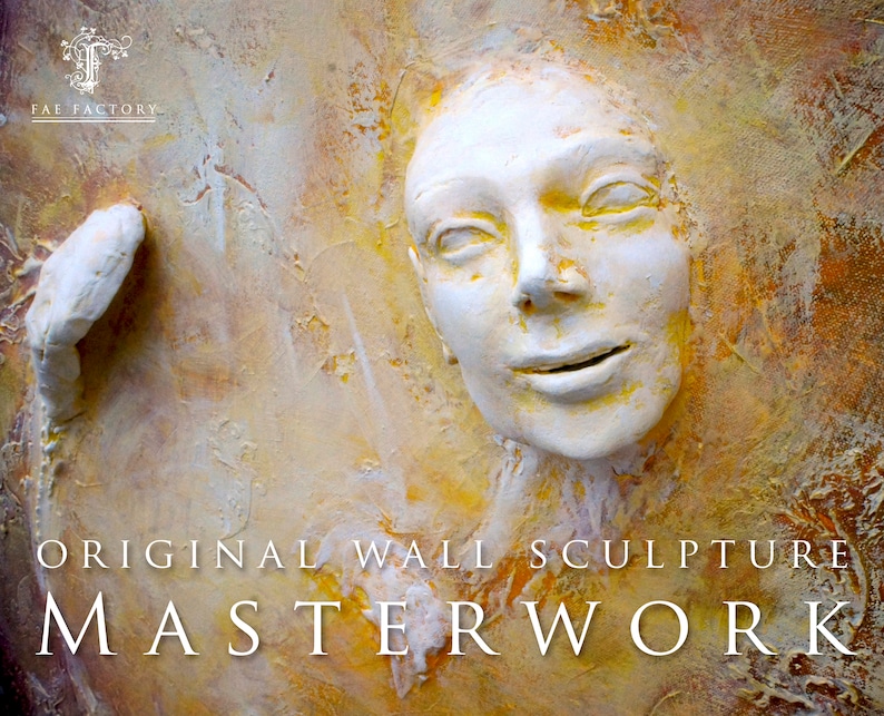 May include: Original wall sculpture artwork featuring a white, textured face with a subtle smile. The background is a warm, yellow and orange colour.