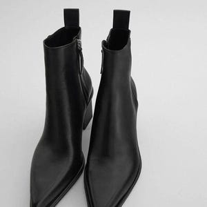 May include: A pair of black leather ankle boots with pointed toes. The boots have a side zip and a small heel. The boots have a pull tab at the top of the shaft.