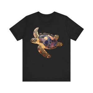 May include: A black short-sleeve t-shirt featuring a graphic of a sea turtle with a shell patterned in shades of blue, purple, and gold, resembling kintsugi pottery. The text "My Kintsugi Era" is printed in a light script font above the turtle.