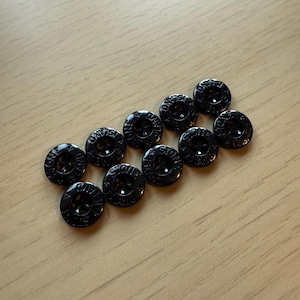 May include: A group of 12 black buttons with the words "Stone Island" embossed on them.