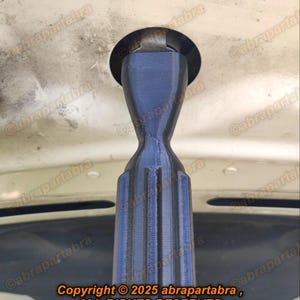 Op de afbeelding: Een zwarte kunststof autoantenne met een geribbeld ontwerp. De antenne is bevestigd aan een witte auto.