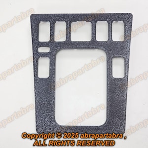 以下が含まれることがあります： 長方形の開口部がある、暗い灰色の質感のあるプラスチック製の車のコンソールトリム。トリムには大きな中央の開口部と、上部と側面に小さな開口部があります。「Copyright © 2025 abrapartabra, ALL RIGHTS RESERVED」の文字が見えます。