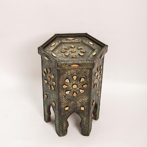 Peut inclure: Une table d'appoint hexagonale antique avec des incrustations et des métaux ouvragés complexes. La table présente une finition sombre et vieillie avec des motifs floraux et géométriques. Les pieds ont un design en arc. Un meuble unique.