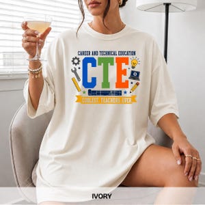 May include: An ivory t-shirt featuring the text CAREER AND TECHNICAL EDUCATION and CTE in blue, green, and orange. The design includes icons of a gear, wrench, ruler, lightbulb, laptop, and pencil, with the text COOLEST. TEACHERS. EVER. below.