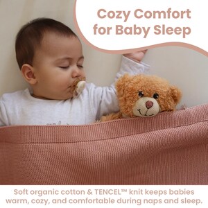 Może przedstawiać: Śpiące dziecko ze smoczkiem i misiem pod r&oacute;żowym dzianinowym kocem. Obraz zawiera tekst "Cozy Comfort for Baby Sleep" i "Soft organic cotton & TENCEL knit keeps babies warm, cozy, and comfortable during naps and sleep."