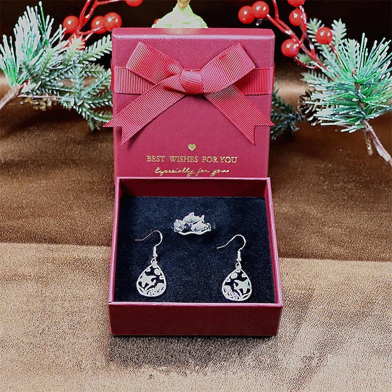 May include: A red gift box with a white bow and the text "Best Wishes for You, Especially for you". The box contains a silver ring and two silver earrings with a floral design.