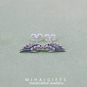 May include: A pair of silver earrings with a wing design and small clear stones.