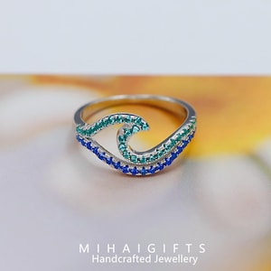 May include: A white ceramic mug with a black handle and the text "But First, Coffee" in a black, handwritten-style font. The mug is on a white surface.