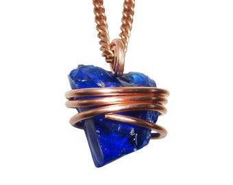May include: A blue crystal pendant necklace. The raw, faceted blue crystal is wrapped in copper wire and suspended from a copper chain. The pendant is centered against a white background.