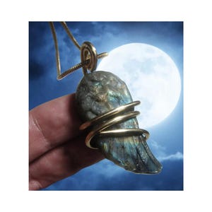 May include: A labradorite gemstone pendant wrapped in gold wire, with a blue, green and gold iridescent sheen. The pendant is hanging from a gold chain.