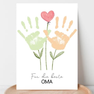 Könnte beinhalten: Eine weiße Karte mit einem Aquarelldesign mit grünen und pfirsichfarbenen Handabdrücken, die Blumenstiele bilden. Ein rosa Herzballon schwebt darüber. Der Text "Für die beste OMA" ist in eleganter Schrift geschrieben.