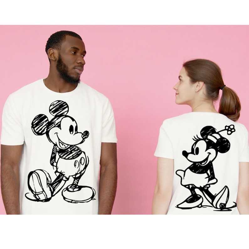 Pode incluir: T-shirts brancas com esbo&ccedil;os pretos de Mickey e Minnie Mouse. Uma t-shirt mostra Mickey na frente, a outra Minnie nas costas. Ambas t&ecirc;m gola redonda e mangas curtas, perfeitas para uso casual.