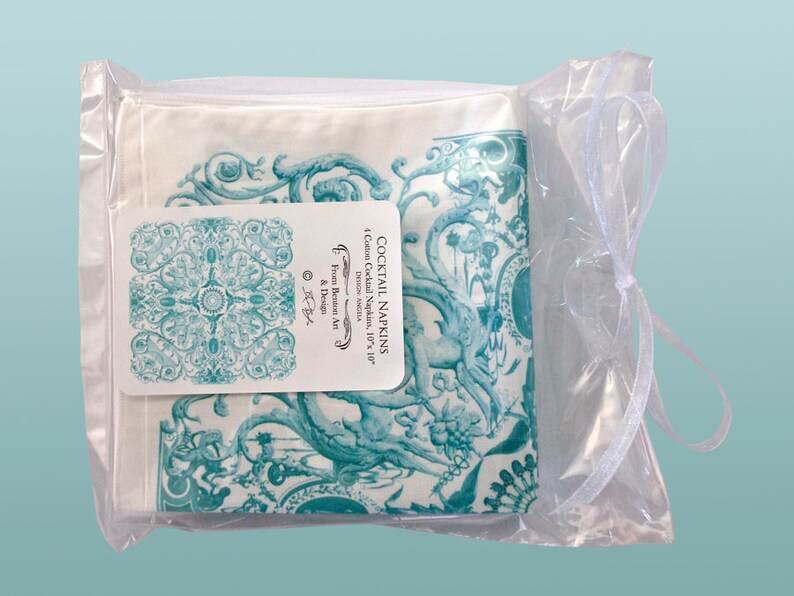 May include: A set of four 10-inch by 10-inch cotton cocktail napkins with a teal and white floral design. The napkins are packaged in a clear plastic bag with a white ribbon. The packaging label reads "Cocktail Napkins, 4 Cotton Cocktail Napkins, 10"x 10", Demon Angela, From Demon Art & Design."